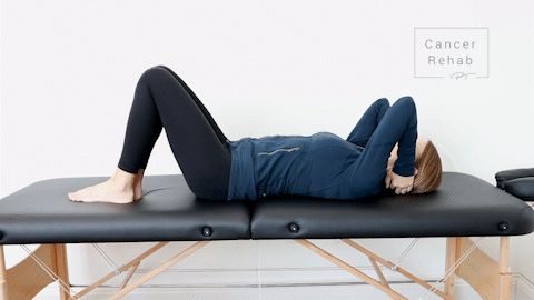 female physical therapist lying on her back on a massage table doing a pec stretch exercise with her hands behind her head