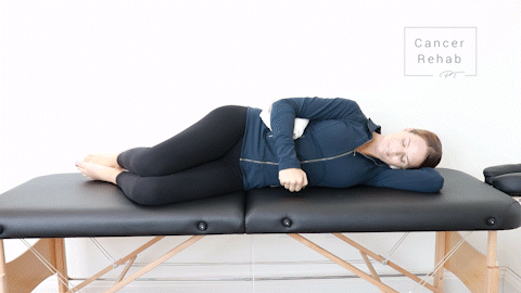 female physical therapist lying on her side on a massage table doing a rotator cuff exercise