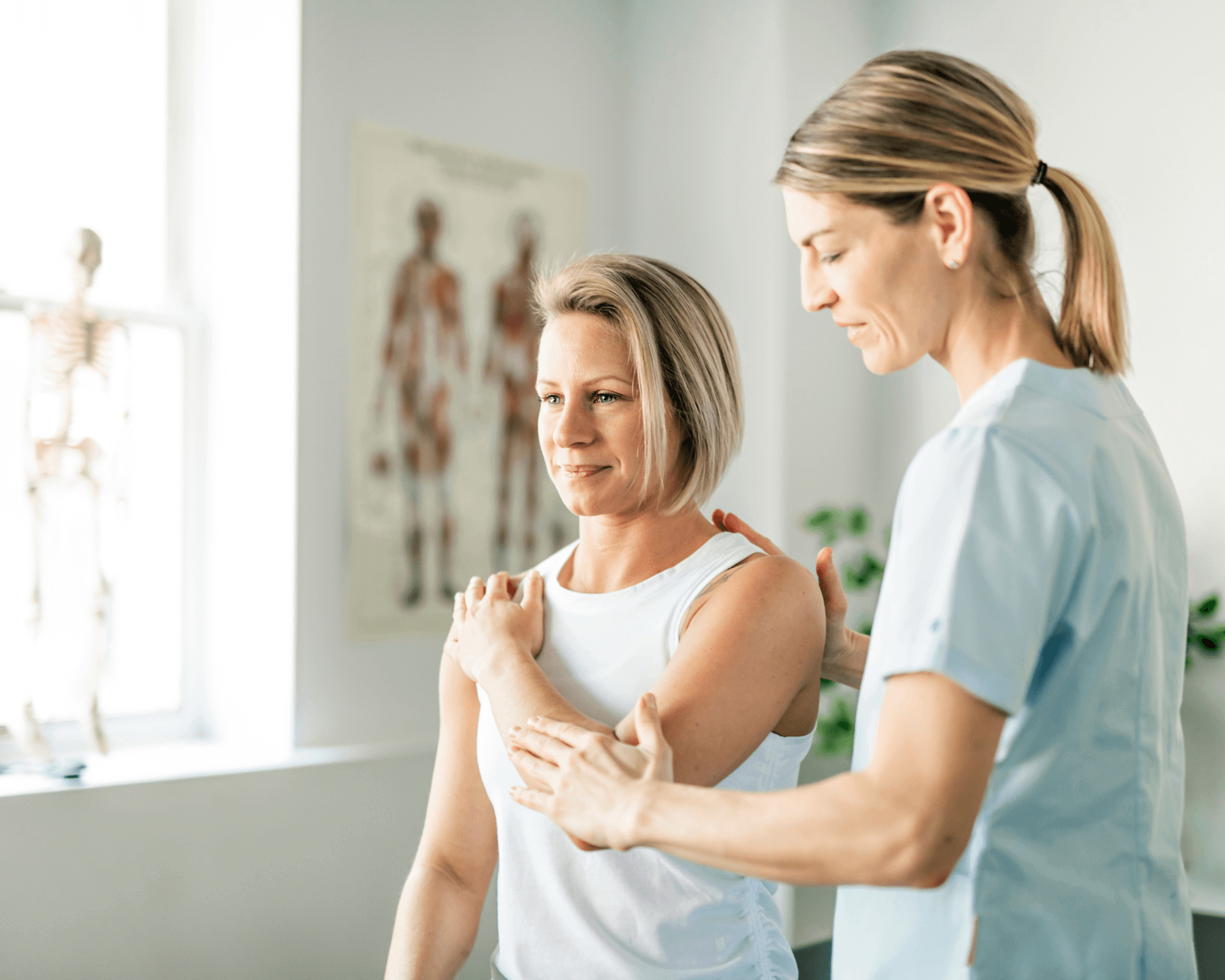 A healthcare professional assists a woman with a shoulder exercise in a brightly lit clinic, referencing the Breast Cancer Rehab online program