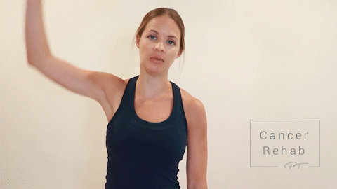 Female Physical therapist navy tank top doing trunk side bends for arm lymphedema