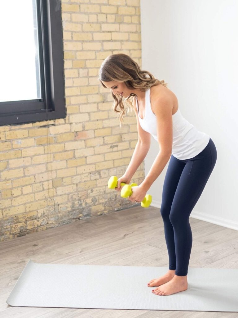 Kelly, a lymphedema physical therapist, holding yellow dumbbells doing a bent over row.