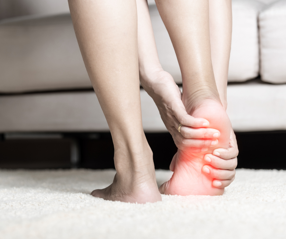 A person sitting and holding their foot with both hands, highlighting foot pain for neuropathy in the sole with a red glow effect around the toes and ball of the foot.