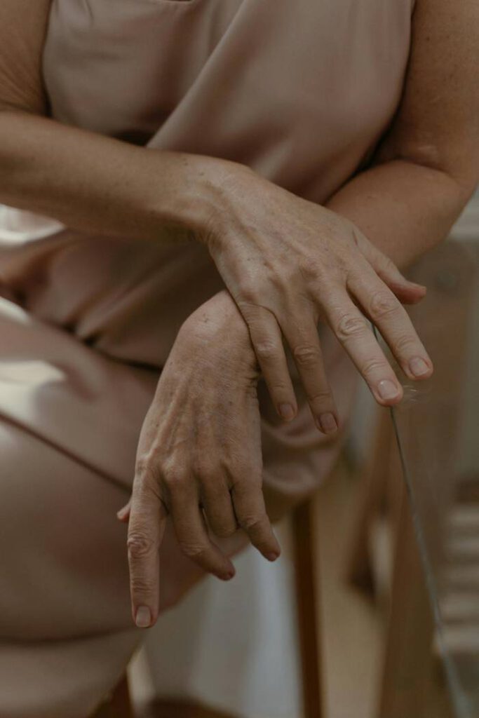 close up of woman's hand draped over themselves with pink dress faded in the background