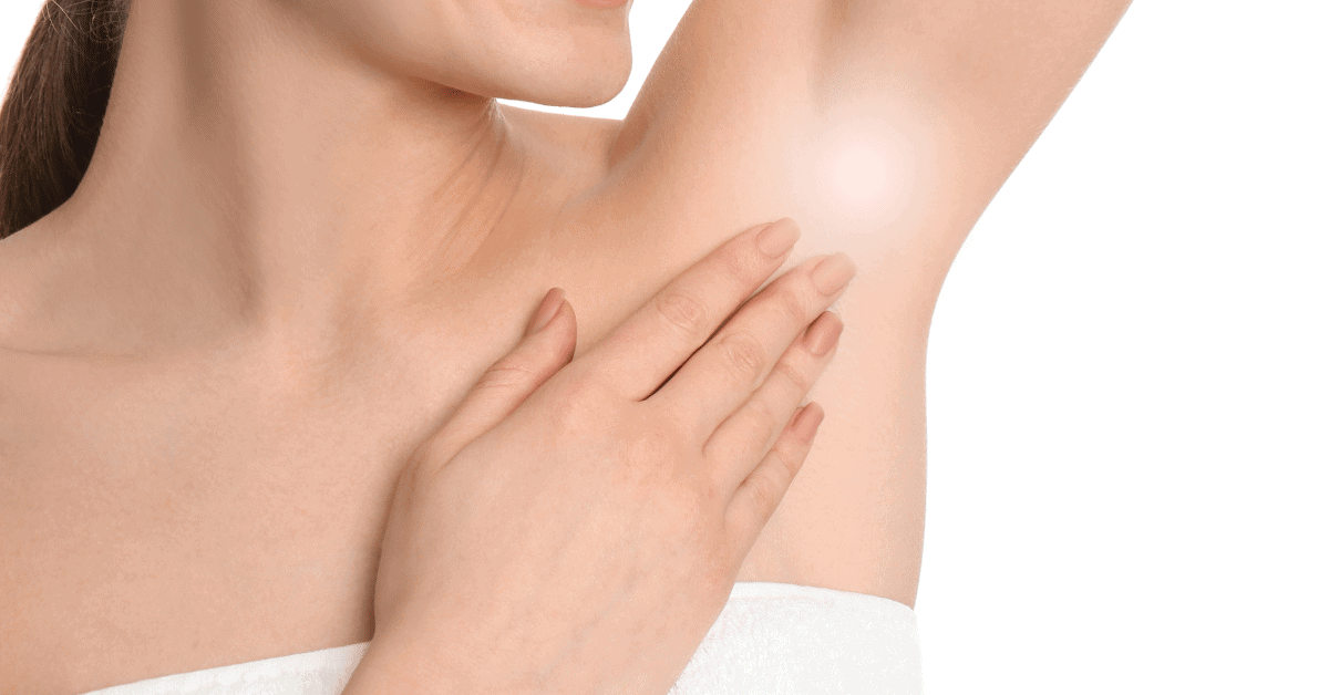 A woman with smooth skin smiles as she touches her armpit, which is highlighted with a soft glow—for those concerned about swelling under the armpit. She wears a white towel against a plain white background.