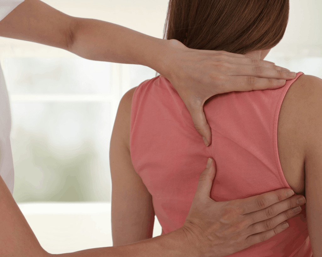 woman in pink tank with therapist hands on shoulder blade, doing physical therapy for cancer patients.