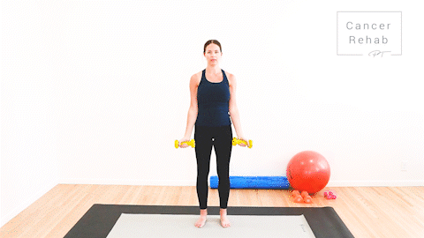 animated clip of physical therapist standing on a yoga mat, holding yellow dumbbells, demonstrating a bicep curl, bending elbows up and down