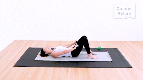 animated clip of physical therapist lying on a yoga mat, raising a dowel up overhead with both arms