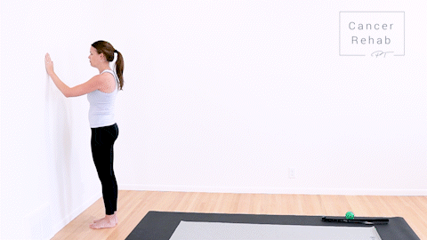 animated clip of physical therapist standing in front of a wall, letting her right arm slide up the wall for a stretch