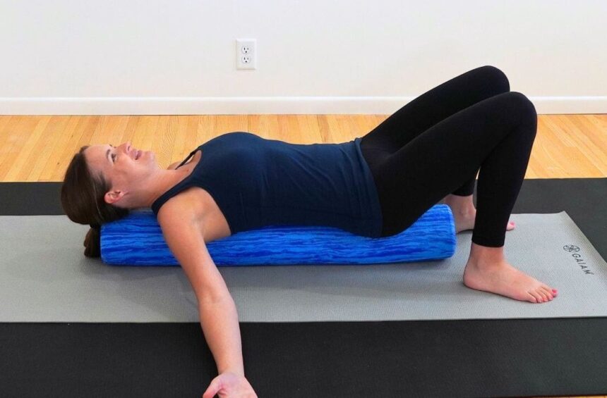a physical therapist lying on a blue foam roller demonstrating an after breast cancer surgery exercise