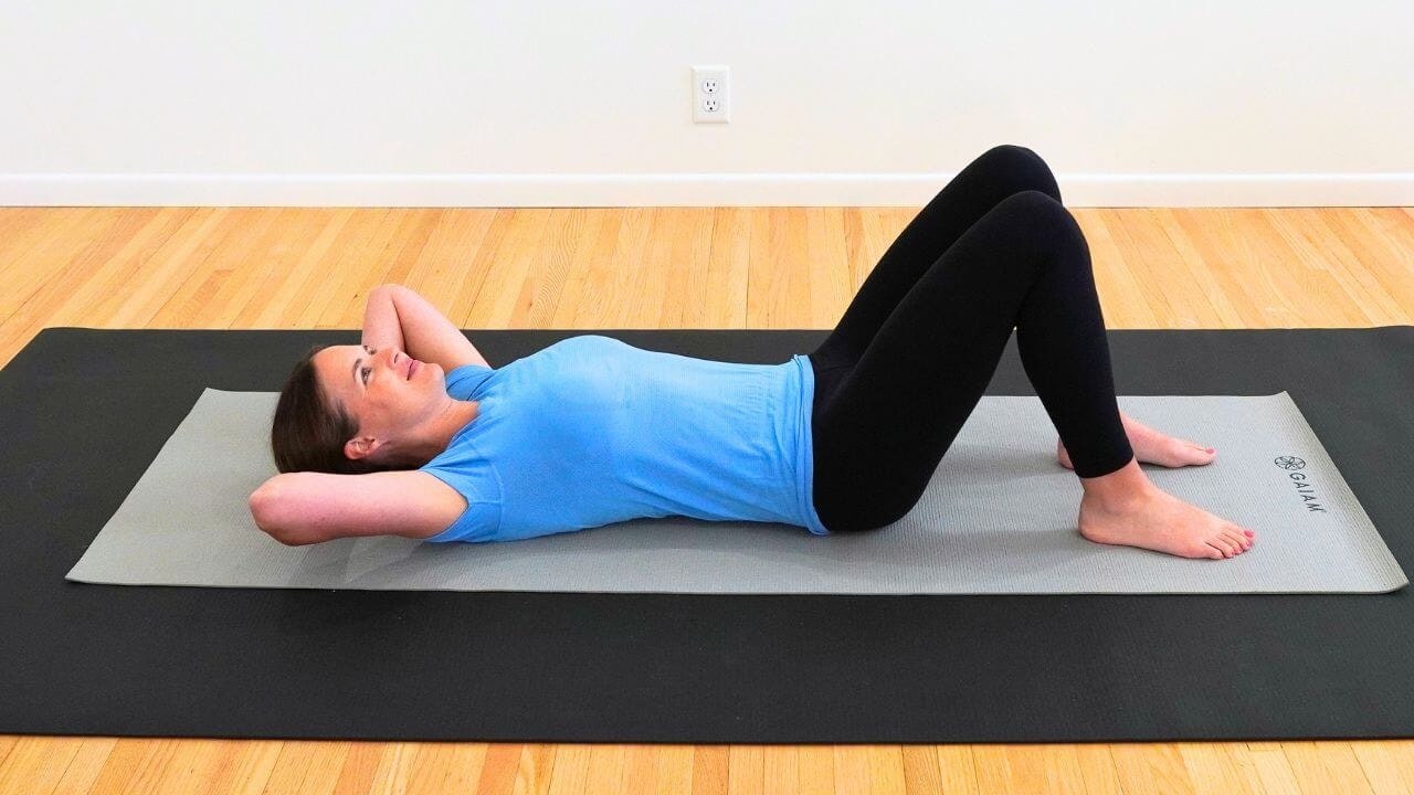 a physical therapist lying on a yoga mat demonstrating exercises after breast cancer surgery