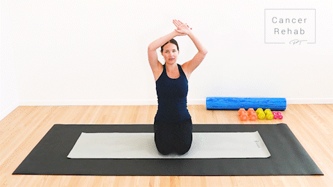 animated clip of physical therapist kneeling on a yoga mat, grabbing left wrist and pulling up and over body for a side stretch