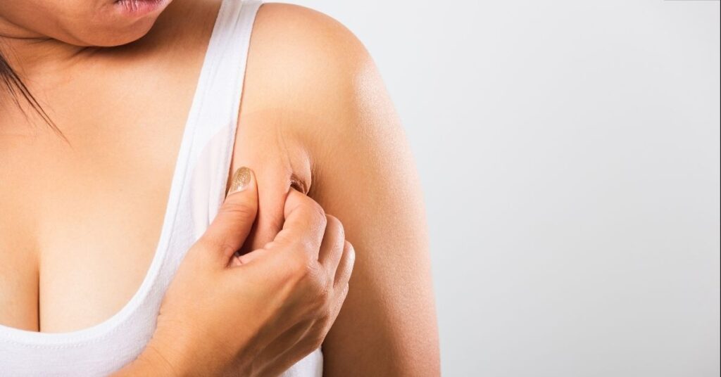 An woman pinching the swollen lymph nodes in her armpit.