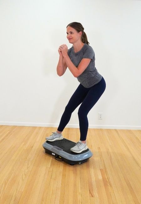 Kelly Sturm, physical therapist in gray shirt and black pants, standing on gray vibration plate doing a side lunge