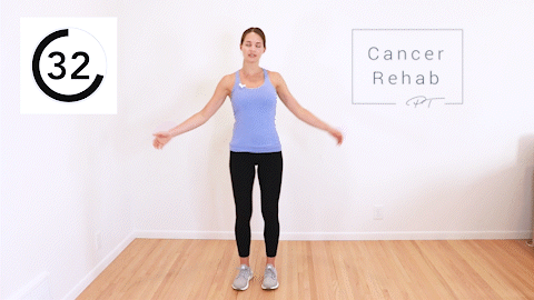 A woman standing and tapping her hand to her opposite leg as she kicks.