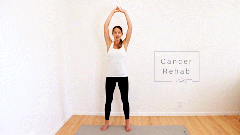A certified lymphedema therapist standing tall with arms above head and palms together. She is bending at the waist and rotating her arms around her body.
