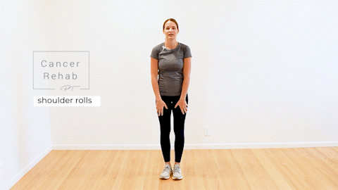 A certified lymphedema therapist standing tall and shrugging both shoulders back and down.