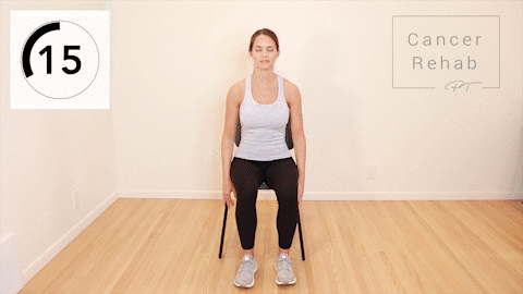 A woman sitting in a chair doing a modified crunch. She is leaning back slightly with a straight back, before sitting back up.