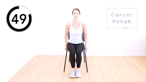 A woman sitting in a chair and stepping her foot out to the side, then back to center.